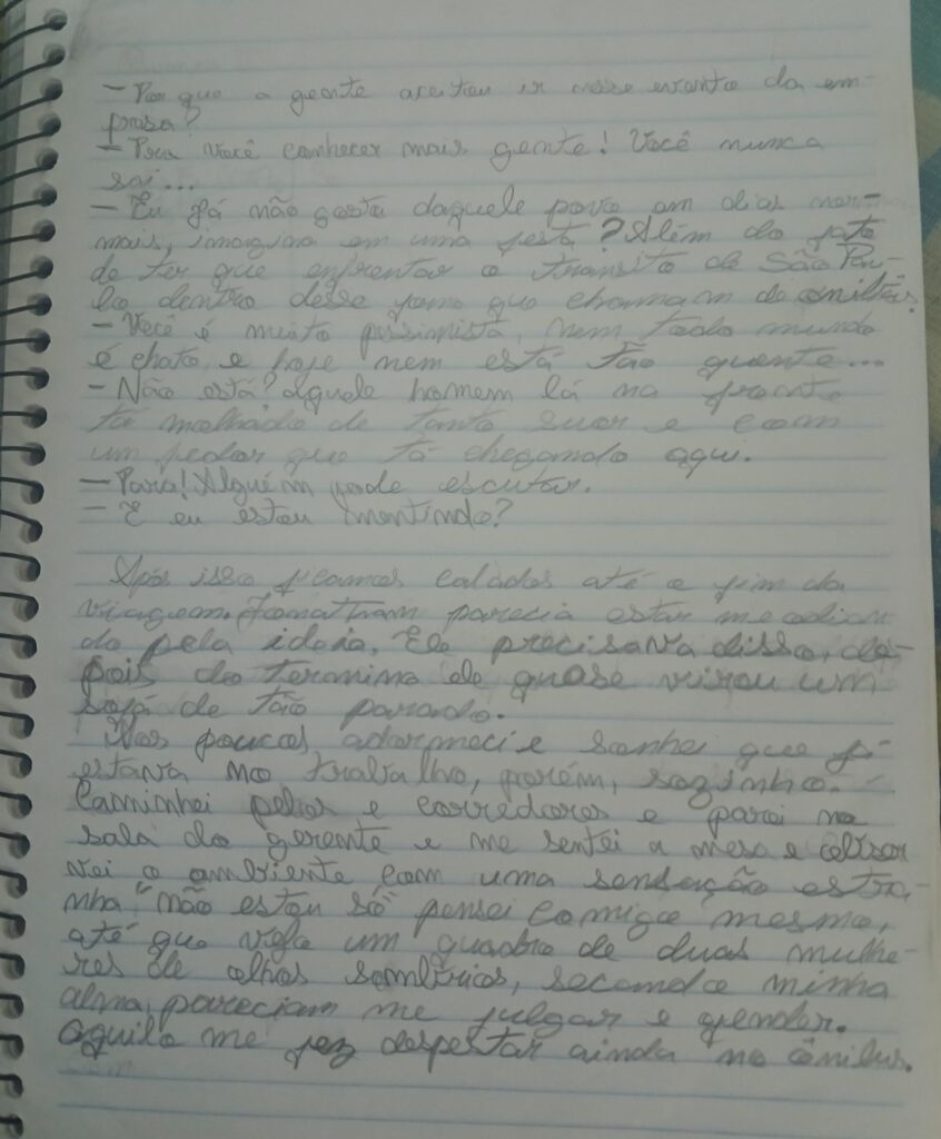 Fotografia de uma página de caderno com espiral contendo texto manuscrito em letra cursiva e tinta azul sobre papel pautado